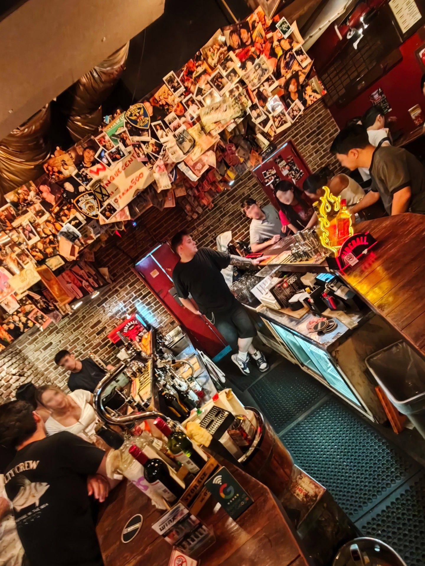 A busy night at the bar counter under a ceiling covered in customers' photos