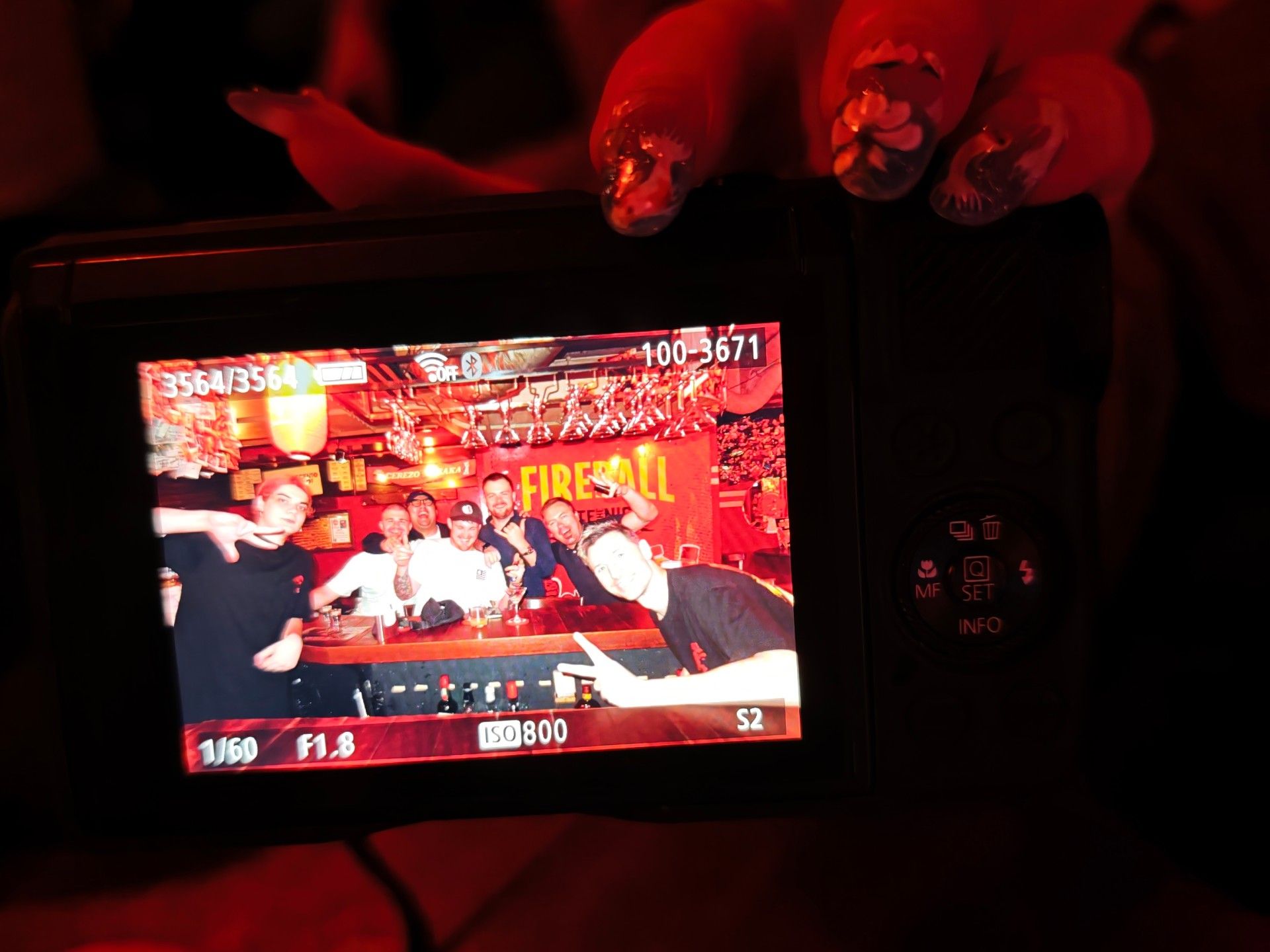 A camera screen showing friends posing at the bar