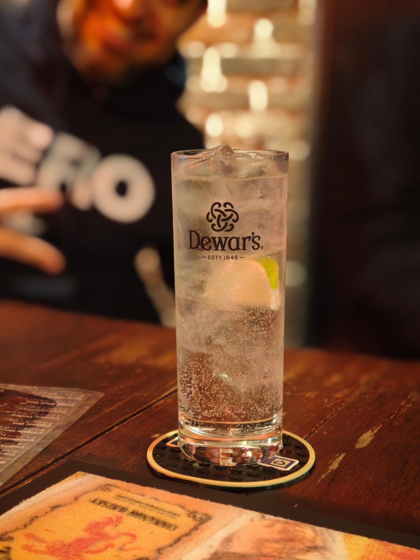 A highball with lime on the wooden bar counter