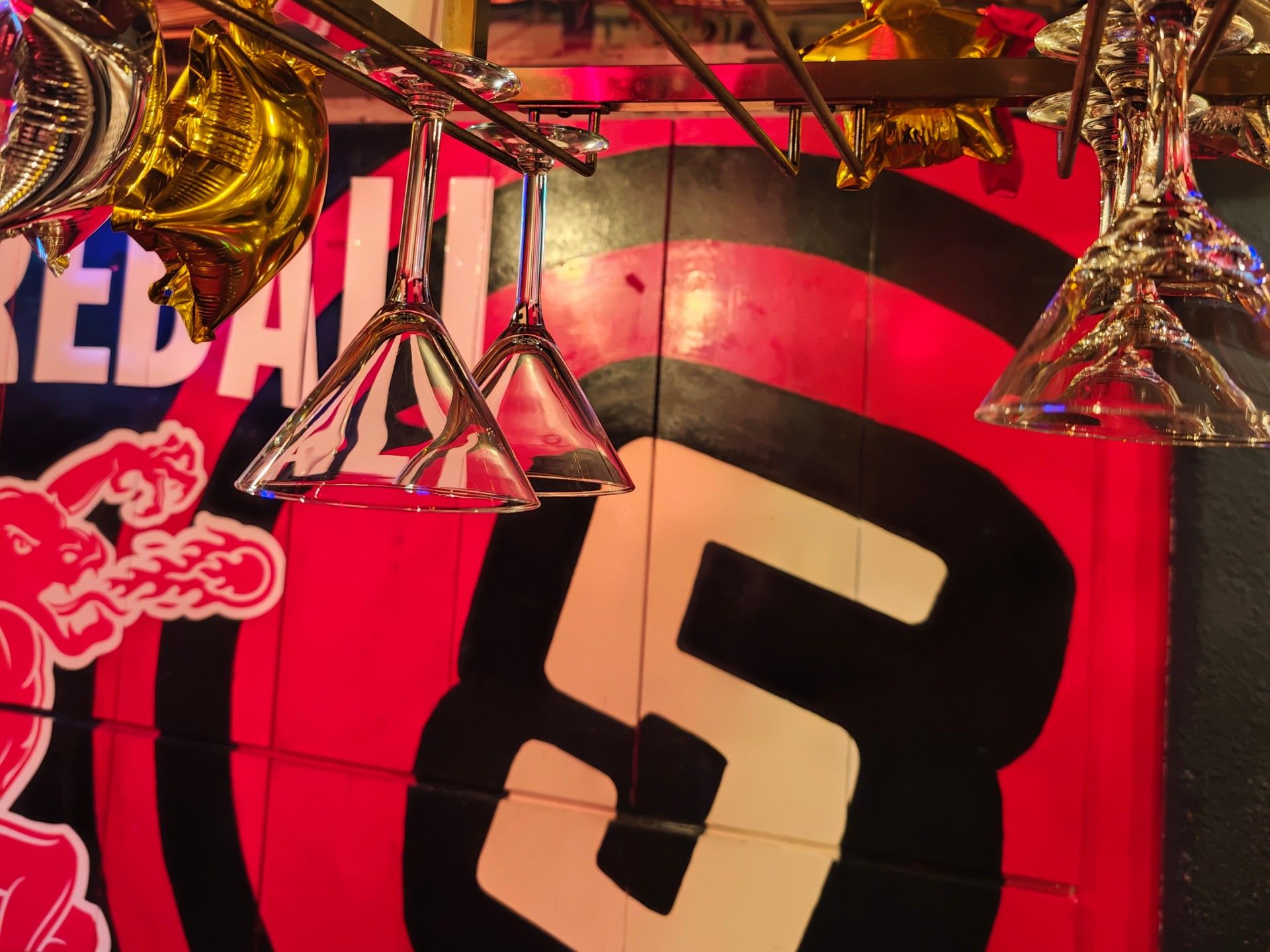 Martini glasses hanging in front of the big red 5 painted on Cinquecento's wall